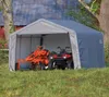 A gray fabric shelter with an orange tiller and a red ATV inside, set in a grassy yard with trees and a barn in the background. Produktbild-Vorschau