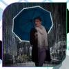 A woman holding a blue umbrella in the rain on a city street at night. Náhled obrázku produktu