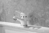 A white faucet with silver accents is shown on a white sink against a textured gray wall. Produktbild-Vorschau
