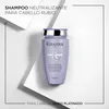 A bottle of Kérastase shampoo is placed on a white surface with geometric shapes creating a minimalist backdrop. Podgląd zdjęcia produktu