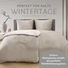 A bed with taupe-colored bedding, pillows, and a duvet, set against a light gray background. Decorative elements like a vase and a branch are visible on the left. Voir les images du produit