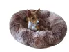 A small dog is resting in a fluffy brown dog bed. Produktbild-Vorschau