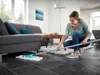 A woman is mopping the floor in a modern living room. Anteprima dell’immagine prodotto