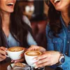 Two women laughing and holding cups of coffee. Produktbild-Vorschau