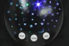 A close-up of a black star projector with blue and green stars and moons. Produktbild-Vorschau