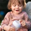 A baby is holding a baby bottle. Anteprima dell’immagine prodotto