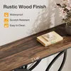 Close-up of a rustic wood finish console table with a book and decorative item on top, and a vase of flowers in the background. Náhled obrázku produktu