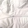 A close-up view of a white quilted mattress protector with a zipper. Produktbild-Vorschau