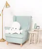 A plush octopus toy sits on a light blue armchair next to two small side tables. Produktbild-Vorschau