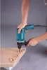 A person is using a Makita hammer drill to drill holes in a piece of wood. Podgląd zdjęcia produktu