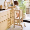 A young child is standing on a wooden step stool in a kitchen, reaching for items on the counter. Náhľad obrázku produktu