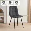 A dark gray upholstered dining chair with tufted detailing and black metal legs, set against a light-colored wall with wooden slats and a partial view of a white shelving unit. Overlay badges provide product information. Náhled obrázku produktu