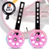Close-up of pink training wheels with LED lights and a black bicycle bell with text. Produktbild-Vorschau