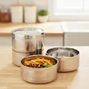 A stack of stainless steel food containers on a wooden countertop, with kitchen elements in the background. Produktbild-Vorschau