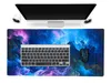 A computer monitor, keyboard, and mouse are placed on a desk with a large, colorful mousepad. Produktbild-Vorschau