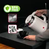 A person is pouring water from a white electric kettle into a black cup. Voir les images du produit