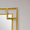 A close-up shot of the corner of a gold metal framed mirror with a geometric design. Produktbild-Vorschau