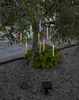 A solar-powered string of colorful LED lights resembling icicles hangs from a small tree in a garden setting. Produktbild-Vorschau
