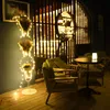 A dimly lit room with a decorative floor lamp and seating area. Produktbild-Vorschau