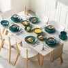 A table set with a teal-colored dinnerware set, featuring various plates and bowls filled with food. Produktbild-Vorschau