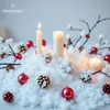A Christmas-themed decoration with candles, pinecones, and ornaments arranged on artificial snow. Náhled obrázku produktu