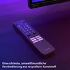 A remote control for a Philips TV is placed on a dark wooden surface, with purple ambient lighting. Voir les images du produit
