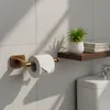 A bathroom setting with a toilet paper holder and a shelf with towels and a plant. Produktbild-Vorschau