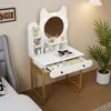 A vanity table with a mirror and lights, set up in a bedroom next to a bed and a plant. Podgląd zdjęcia produktu