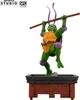 A figurine of Donatello from Teenage Mutant Ninja Turtles, posed dynamically on a brick-like platform. Podgląd zdjęcia produktu