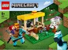 A LEGO Minecraft horse stable playset is shown on a green grassy base, with Minecraft-style terrain in the background. Podgląd zdjęcia produktu