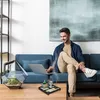 A man is sitting on a couch using a laptop, with a zen garden and a terrarium on a coffee table in front of him. Náhled obrázku produktu