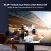 A person is using a smartphone to wirelessly connect to a projector, which is projecting a racing car scene onto a large screen. Produktbild-Vorschau