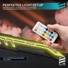 A hand holding a remote control for RGB lighting, with a gaming desk in the background. Produktbild-Vorschau