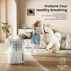A young girl and a white dog are playing in a living room with an air purifier in the foreground. Podgląd zdjęcia produktu