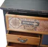 A close-up view of the drawers of a cabinet, showing decorative patterns and a sign. Podgląd zdjęcia produktu