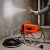 A person is using an orange paint sprayer to paint a concrete wall. Produktbild-Vorschau