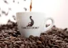 A white coffee cup with the Chicco d'Oro logo is surrounded by coffee beans, with coffee being poured into it. Produktbild-Vorschau