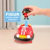 A child's hand is holding a small red toy figure above a red toy bumper car. An arrow indicates the figure is to be placed into the car. Produktbild-Vorschau