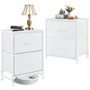 Two white fabric drawer nightstands are shown against a white background. One nightstand has a lamp and books on top, while the other has books and decorative items. A robot vacuum cleaner is positioned underneath the left nightstand. Produktbild-Vorschau