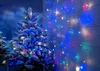 A frosted Christmas tree decorated with colorful LED lights, placed next to a white wooden wall with more string lights. Produktbild-Vorschau