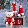 A Christmas-themed display featuring a teddy bear, a wooden Christmas tree, a Santa Claus figure, and a wooden perpetual calendar. Náhled obrázku produktu