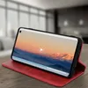 A red flip cover case for a smartphone is shown on a wooden table, with the phone displaying a video. Produktbild-Vorschau