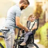 A father is securing his daughter into a bicycle child seat. Náhled obrázku produktu