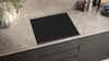 A modern kitchen countertop with a black induction hob. Produktbild-Vorschau