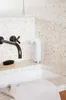 A white soap dispenser sits on a countertop next to a sink, with a black faucet and a brush. Anteprima dell’immagine prodotto