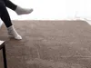 A person's legs wearing socks are resting on a plush rug. Produktbild-Vorschau
