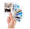 A hand holding a fan of Fujifilm Instax Mini photos. Produktbild-Vorschau