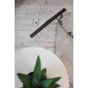 A close-up view of a floor with a rug, a plant on a white table, and a black infrared heating mat with its power cord and controller. Náhled obrázku produktu