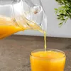 Orange juice is being poured from a glass pitcher into a glass. Podgląd zdjęcia produktu