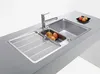 A stainless steel kitchen sink with a faucet and a small bowl of fruit on a countertop. Produktbild-Vorschau